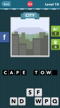 Greyish buildings with green trees and mountains behind them|